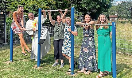 Diakon Manfred M&uuml;ller und zweite B&uuml;rgermeisterin Elisabeth Assmann zusammen mit dem Orga-Team bei der Spielplatzsegnung im Juni 2025 mit dem neu angeschafften Reck