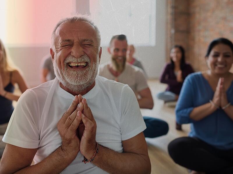 Smiling old man in yoga class Lach-Yoga ist nur einer von vielen originellen oder besonderen Kursen im Programm der Volkshochschulen. In Erlangen und Erlangen-Höchstadt beginnt diesen Monat das Herbst-/Wintersemester mit abwechslungsreichen Kursen. (Symboldbild)