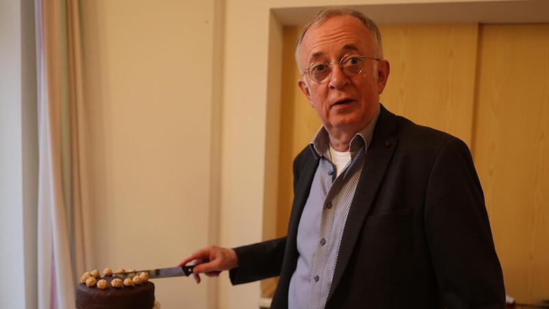 Pfarrer Hans Roppelt schneidet seine dreistöckige Geburtstagstorte höchstpersönlich an.