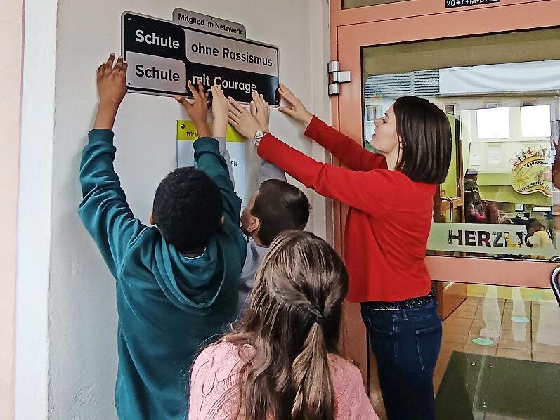 Gemeinsam bringen Sch&uuml;ler und Lehrer das neue Schild an.