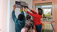 Gemeinsam bringen Sch&uuml;ler und Lehrer das neue Schild an.