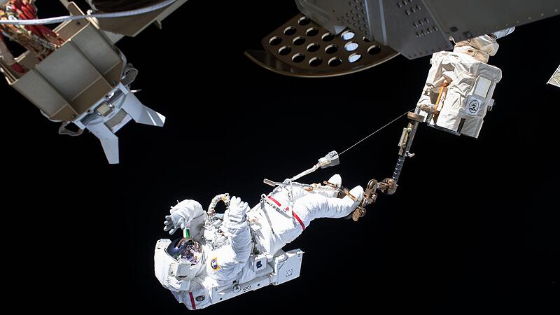 Ein ESA-Astronaut ist bei einem Au&szlig;eneinsatz an der Internationalen Raumstation ISS &uuml;ber den Roboterarm Canadarm2 gesichert. Bayern entwickelt sich  zu einem der wichtigsten Raumfahrt-Standorte in Europa.