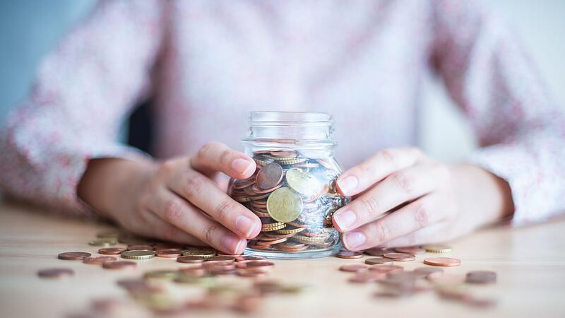 Eine Frau hält ein mit Münzen gefülltes Glas