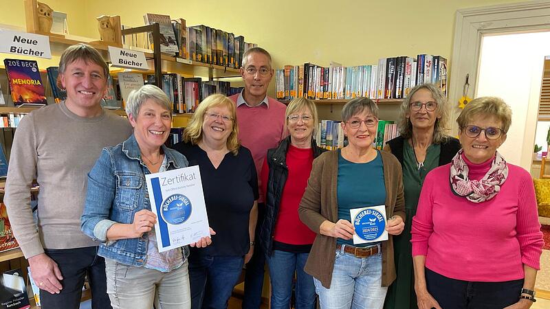 Zum Erhalt des goldenen Siegels gratulieren B&uuml;rgermeister Rainer Morper (links) und Pastoralreferent Dirk Rudolph (Mitte) Mitgliedern des Teams um die B&uuml;chereileiterin Christine Neder (2. von links).