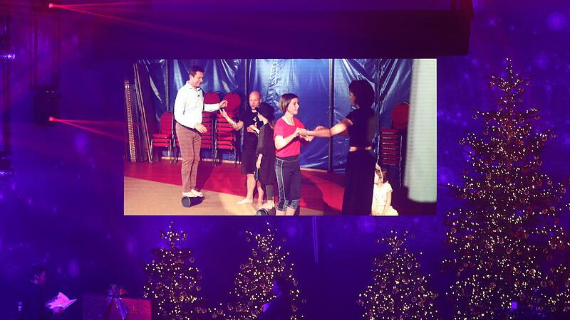 Auf riesigen Bildschirmen neben den festlich geschm&uuml;ckten B&uuml;hnen-B&auml;umen wird der Beitrag &uuml;ber das Mitmachen im &bdquo;Zirkus Giovanni&ldquo; gezeigt.