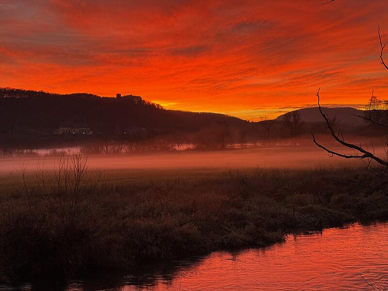 &bdquo;Fotografiert gestern kurz nach 16.30 Uhr vom Steg im Hof des Museums Herrenm&uuml;hle an der Fr&auml;nkischen Saale in Hammelburg. Zu sehen sind die Saalewiesen, aus denen der Nebel aufzieht, die Fr&auml;nkische Saale und im Hintergrund Schloss Saaleck im Feuerhimmel.&ldquo;