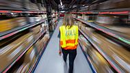 Eine Zollbeamtin l&auml;uft durch ein Paketlager
