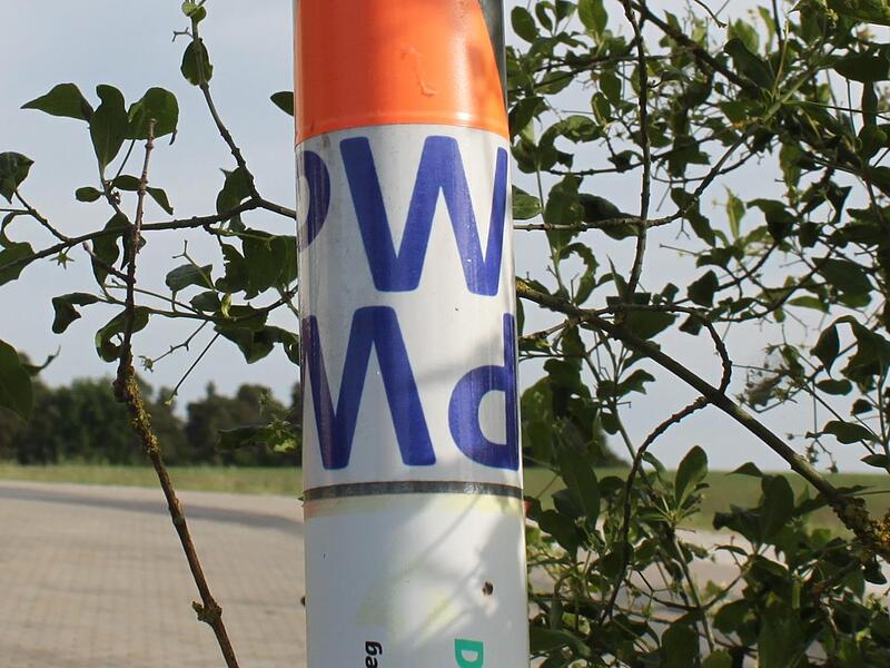 Unscheinbare, aber  wichtige Wegmarken: Aufkleber mit Richtungspfeil  an einem Schildmast auf dem Lauberberg.