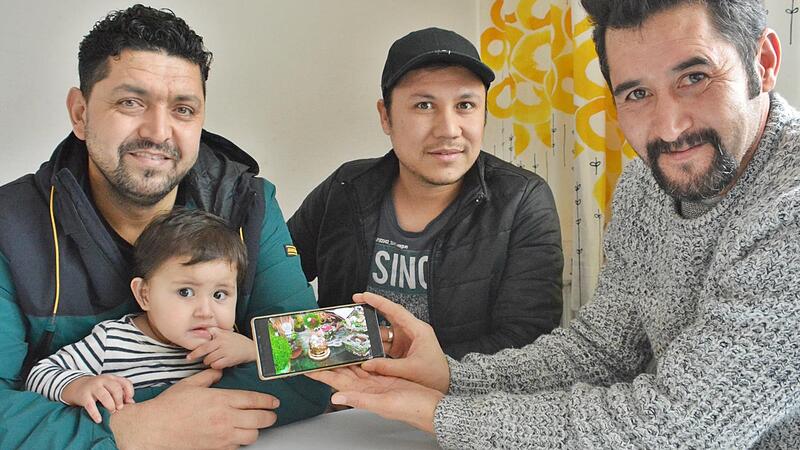 Hedayatullah Muslih, Muhammad Wafa und Sayed Eshag zeigen auf dem Handy, wie so ein Frühlingsfest an Neujahr in Afghanistan gefeiert wird. Da steht dann gutes Essen auf dem Tisch und alles ist geschmückt.