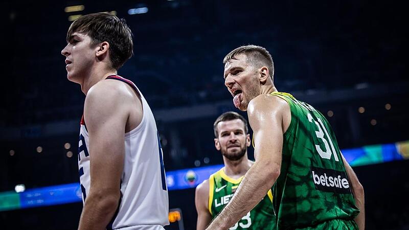 Vaidas Kariniauskas (rechts), vor einem Jahr noch Spieler von Brose Bamberg, streckt dem Amerikaner Austin Reaves nach einer erfolgreichen Aktion die Zunge heraus. Im Hintergrund beobachtet sein Mitspieler Tomas Dimsa die Aktion des Point Guards.