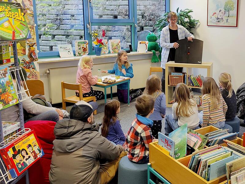 Gebannt lauschten Ronja und Sophie (am Tisch) und zahlreiche andere Kinder und Erwachsene dem Erzähltheater von Claudia Hofmann beim Nachmittag der offenen Tür in der Gemeindebücherei Großenseebach.