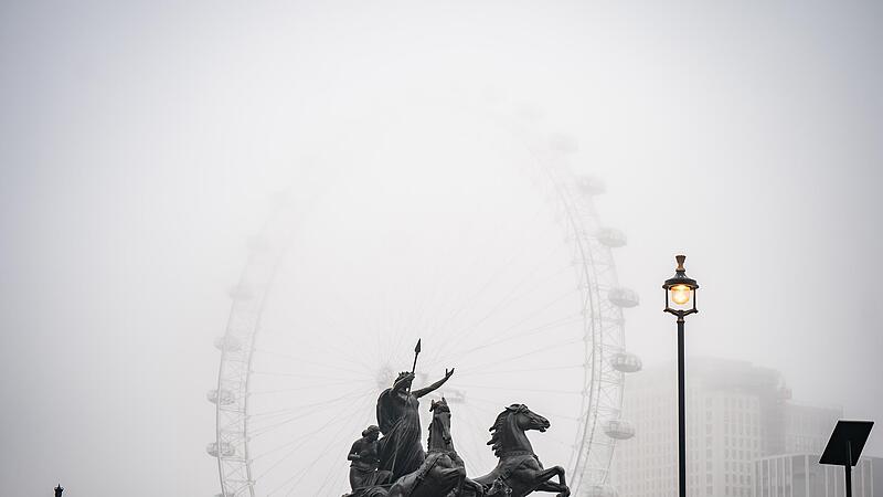 Trübe Aussichten: Arbeiter reinigen die Boudiccan Rebellion Statue am Victoria Embankment, während Nebel das London Eye am Südufer der Themse umgibt.