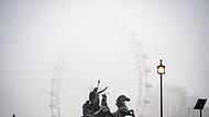 Trübe Aussichten: Arbeiter reinigen die Boudiccan Rebellion Statue am Victoria Embankment, während Nebel das London Eye am Südufer der Themse umgibt.