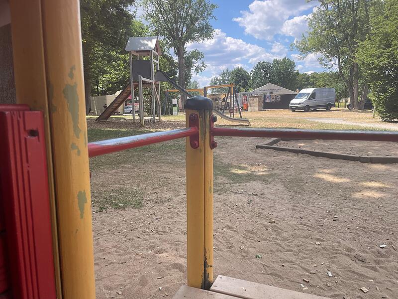 Das H&auml;uschen im Sandkasten. Von Holz und Metall der Spielger&auml;te bl&auml;ttert die Farbe ab.