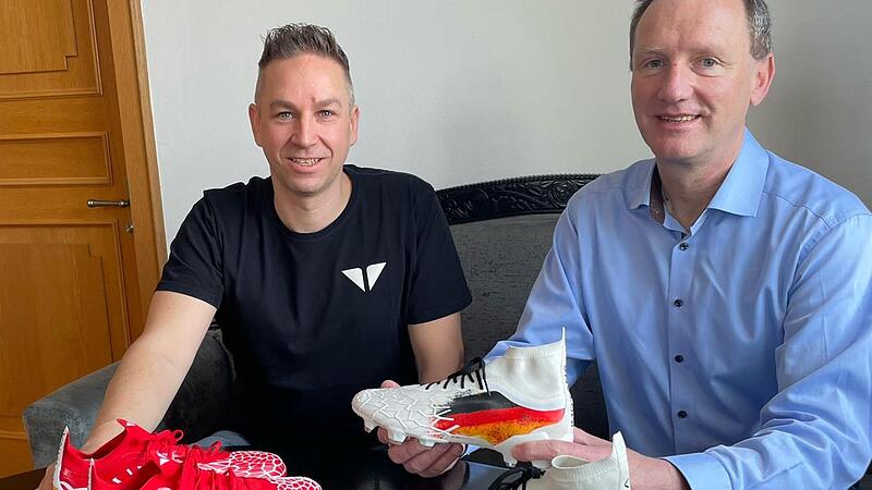 Gesch&auml;ftsf&uuml;hrer Benjamin Dorsch (links) stellt sich mit zwei neuen Fu&szlig;ballschuhen von Imotana bei B&uuml;rgermeister Michael Ziegler vor, der sich dar&uuml;ber freut, dass das Start-Up-Unternehmen seinen Gesch&auml;ftssitz nach Eltmann verlegt hat.