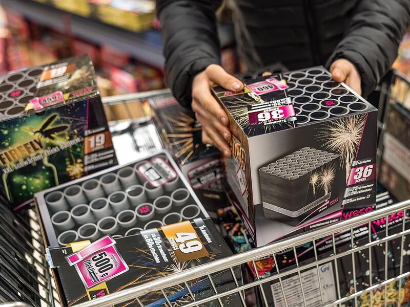 Eine Person legt Feuerwerk in einen Einkaufswagen