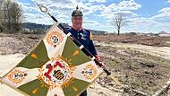 Besondere Erinnerung an Prinz Andreas: Mike Donner zeigt die besondere Fahne des Spielmannszugs der Freiwilligen Feuerwehr Eisfeld. Und die passende Uniform plus Pickelhaube trägt er gleich auch noch dazu.