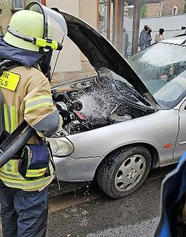 Feuerwehrmann beim Löschen am Fahrzeug