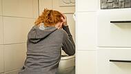 Frau kniet vor einer Toilette
