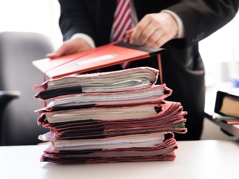 Ein Staatsanwalt steht vor einem Stapel Gerichtsakten