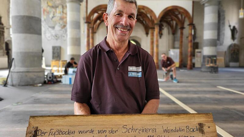 Werner Back hält das Holzbrett in Händen, das er zusammen mit seinen jungen Arbeitskollegen 1977 bei der letzten Kirchensanierung beschriftet und in den Dielenboden verlegt hatte.