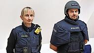 Julia Frohna in ganz normaler Einsatzausrüstung, Christian Fleischmann hat zur Demonstration die schwere ballistische Schutzweste „SK 4“ übergezogen und den schweren Helm aufgesetzt. Julia Frohna in ganz normaler Einsatzausrüstung, Christian Fleischmann hat zur Demonstration die schwere ballistische Schutzweste „SK 4“ übergezogen und den schweren Helm aufgesetzt.