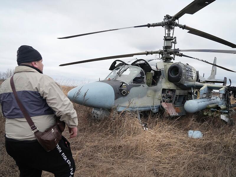 Ein Mann steht nach dessen Notlandung vor einem russischer Ka-52-Kampfhubschrauber außerhalb der ukrainischen Hauptstadt auf einem Feld. Russland hat am Donnerstag einen umfassenden Angriff auf die Ukraine gestartet und Städte und Stützpunkte mit Luftangriffen oder Granaten beschossen.