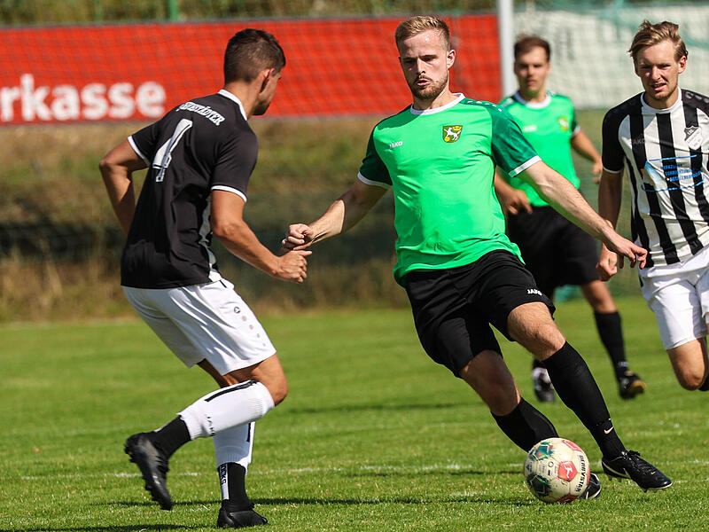 Der Wolfersgrüner Doppeltorschütze Steve Schön (grünes Trikot) läuft auf Christoph Ramming zu.
