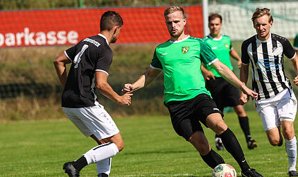 Der Wolfersgrüner Doppeltorschütze Steve Schön (grünes Trikot) läuft auf Christoph Ramming zu.