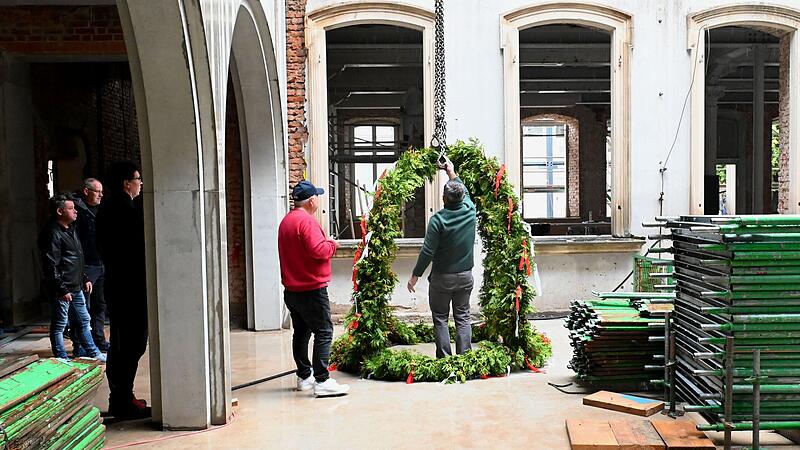 Der Richtfestkranz wird vom Atrium aus aufs Dach gezogen.