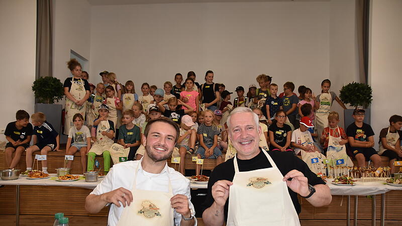 Nicht nur die Kinder hatten viel Spa&szlig; an der Aktion: Landrat Jonas Gleich und Sternekoch Alexander Herrmann signierten Sch&uuml;rzen und erhielten als Dank jeweils eine Sch&uuml;rze, auf der alle Kinder unterschrieben hatten.