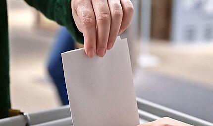 Ein W&auml;hler steckt bei einer Wahl seinen Wahlzettel in eine Urne. Bayernweit finden am 8. M&auml;rz Kommunalwahlen statt.
