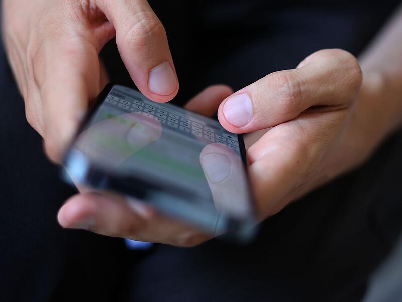 Mann tippt auf einem Smartphone eine WhatsApp Nachricht