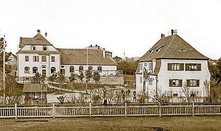 Ein Bilderbuch-Ensemble von 1908: das Eisenbahnerhaus mit der Gastst&auml;tte &bdquo;Fr&auml;nkischer Hof&ldquo; dahinter. Ein Park mit jungen Kastanien verbindet die beiden in Reformarchitektur des fr&uuml;hen 20. Jahrhunderts errichteten Geb&auml;ude.