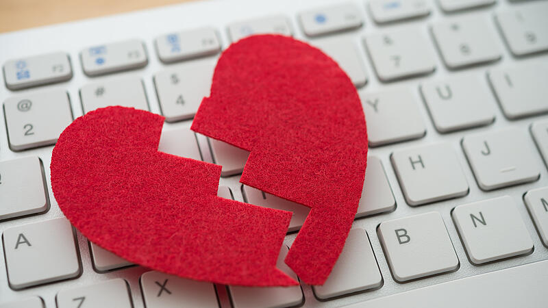 Red broken heart on white keyboard computer background. Online internet romance scam or swindler in website application dating concept. Love is bait or victim.