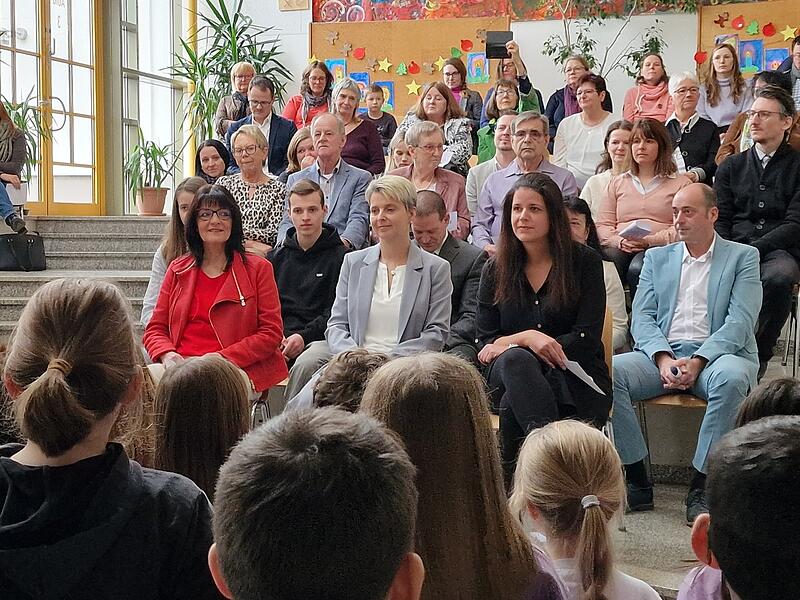 Die neue Schulleitung im Mittelpunkt: Carolin Erb-Heyne (mitte) und Daniela Förg (rechts) nehmen während der Einführungsfeier Platz, umgeben von Gästen und Kollegium der Grundschule Bad Brückenau. Links im Bild Schulamtsdirektorin Birgit Herré.