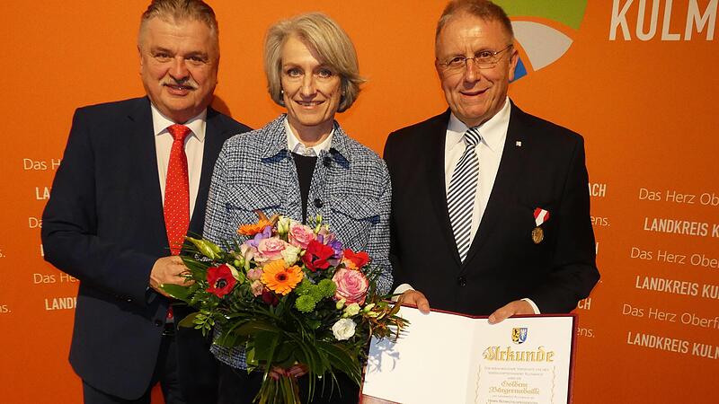 Landrat Klaus Peter S&ouml;llner nimmt die Ehrung f&uuml;r Bezirkstagspr&auml;sident Henry Schramm (in der Mitte Ehefrau Andrea) mit der Goldenen B&uuml;rgermedaille des Landkreises vor.