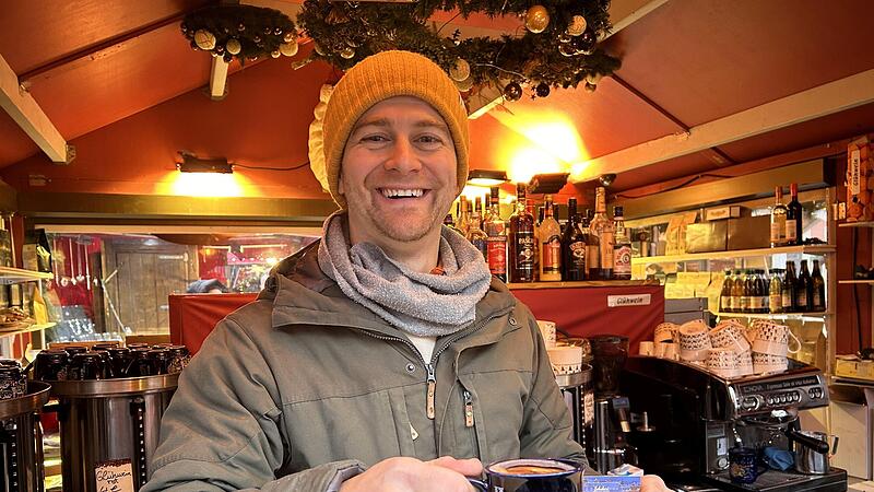 Max Schubart reicht eine Tasse Glühwein. Am Stand des Café Schubart gibt es aber auch Kaffee – und, vor allem: selber gemachten Orangenpunsch! Max Schubart reicht eine Tasse Glühwein. Am Stand des Café Schubart gibt es aber auch Kaffee – und, vor allem: selber gemachten Orangenpunsch!