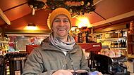 Max Schubart reicht eine Tasse Gl&uuml;hwein. Am Stand des Caf&eacute; Schubart gibt es aber auch Kaffee &ndash; und, vor allem: selber gemachten Orangenpunsch!