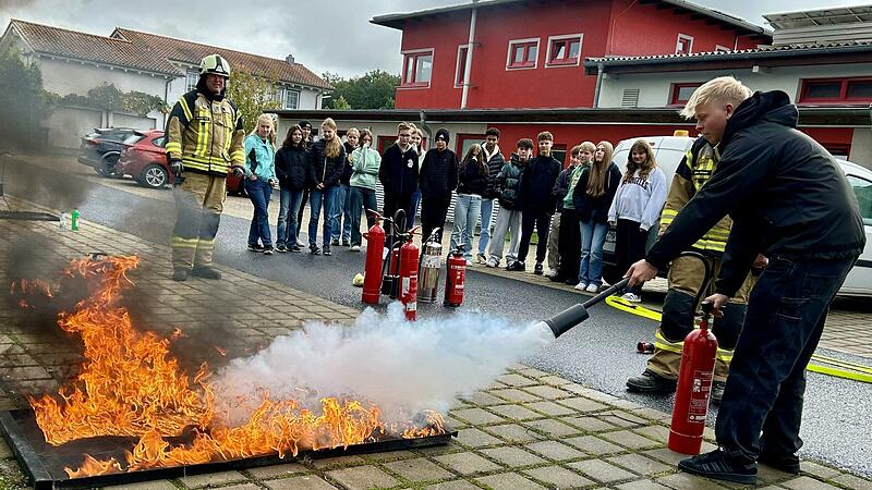 Ein Sch&uuml;ler beim L&ouml;schen eines Benzinbrandes.