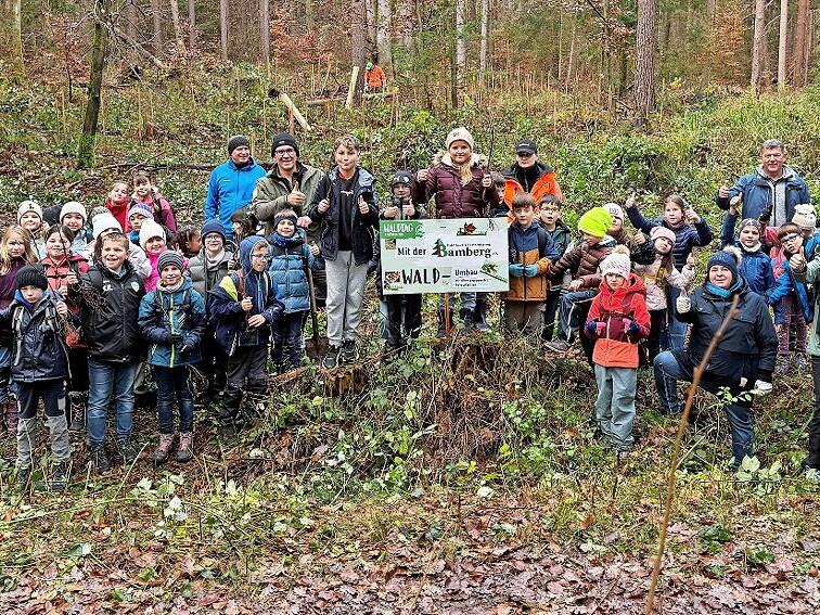 Oberhaids B&uuml;rgermeister Carsten Joneitis, F&ouml;rsterin Amelie Baumer, Angelika Morgenroth von der WBV, Rektor Georg Schmidt sowie Lehrer und Sch&uuml;ler der dritten Klassen der Grund- und Mittelschule Oberhaid bei ihrer Aktion im Wald.