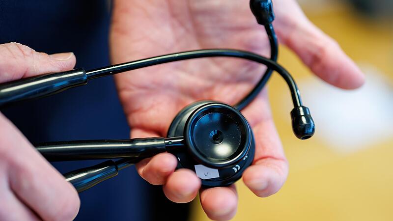 Ein Hausarzt h&auml;lt in seiner Praxis sein Stethoskop in den H&auml;nden.