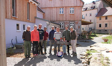 Auf dem Foto von links stehen vor den Wohnh&auml;usern und der M&uuml;hle: Klaus Reichert, Anna Baumgartner, Simon Memmel, Rainer Neubauer, Andr&eacute; und Magdalena Gl&ouml;ckner, Jakob mit Kind sowie Martina Neubauer.