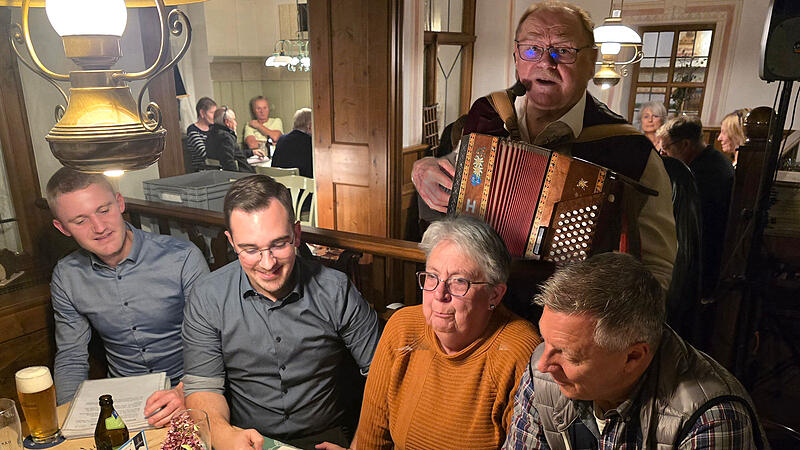 Robert Treuheit mit seiner Ziehharmonika hinter einigen begeisterten S&auml;ngern in Neuhaus.