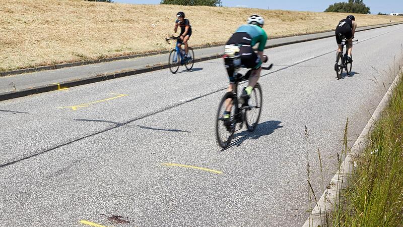 Triathleten fahren auf dem Rad an der Ungl&uuml;ckstelle auf dem Gaueter Hauptdeich vorbei.