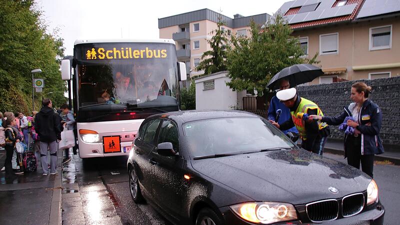 Elterntaxi gegen Schulbus: Der dunkle BMW blockiert die Haltestelle, Polizist Florian Heuring konfrontiert den Fahrer. Elterntaxi gegen Schulbus: Der dunkle BMW blockiert die Haltestelle, Polizist Florian Heuring konfrontiert den Fahrer.