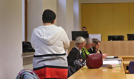 Eine angeklagte Frau (l) und ihr ebenfalls angeklagter Ehemann (3.v.l) stehen und sitzen mit ihren Anw&auml;lten in einen Gerichtssaal im Landgericht. Knapp zwei Jahre nach dem mutma&szlig;lichen Hungertod ihrer Tochter haben die angeklagten Eltern die Verantwortung f&uuml;r das Geschehen &uuml;bernommen.  Laut Staatsanwaltschaft infizierte sich deren 16-J&auml;hrige Tochter kurz vor ihrem Tod im Dezember 2022 mit dem Coronavirus und litt an einer Magen-Darm-Infektion.