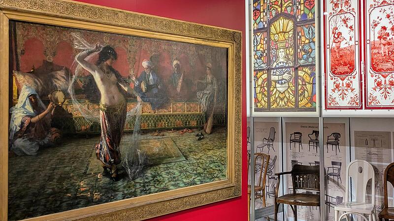 Blick in die Ausstellung mit dem Gem&auml;lde &bdquo;Arabischer Schleiertanz&ldquo; (1893) des Malers Ferdinand Max Bredt sowie Bleiglasfenstern und St&uuml;hlen um 1900