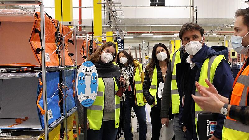 Amazon-Mitarbeiter Maximilian Valentin (rechts) weiht die Pommersfeldener Ratsmitglieder in die Betriebsabl&auml;ufe ein.