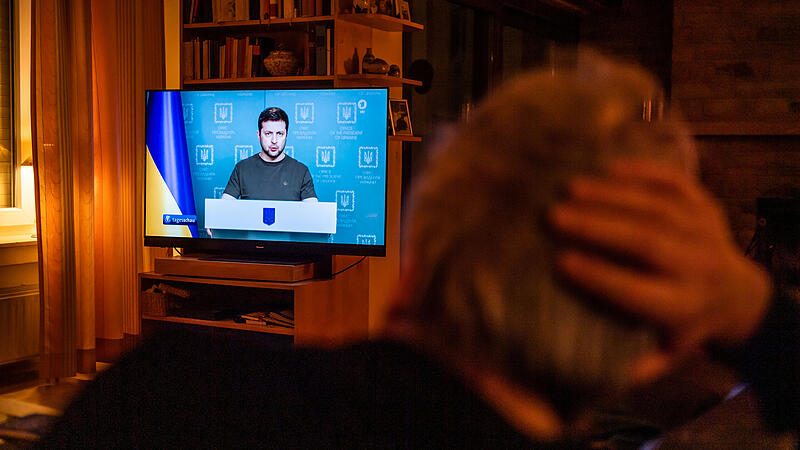 Ein Mann sitzt auf dem Sofa und schaut im Fernsehen die Tagesschau. Die Bilder machen vielen Angst.